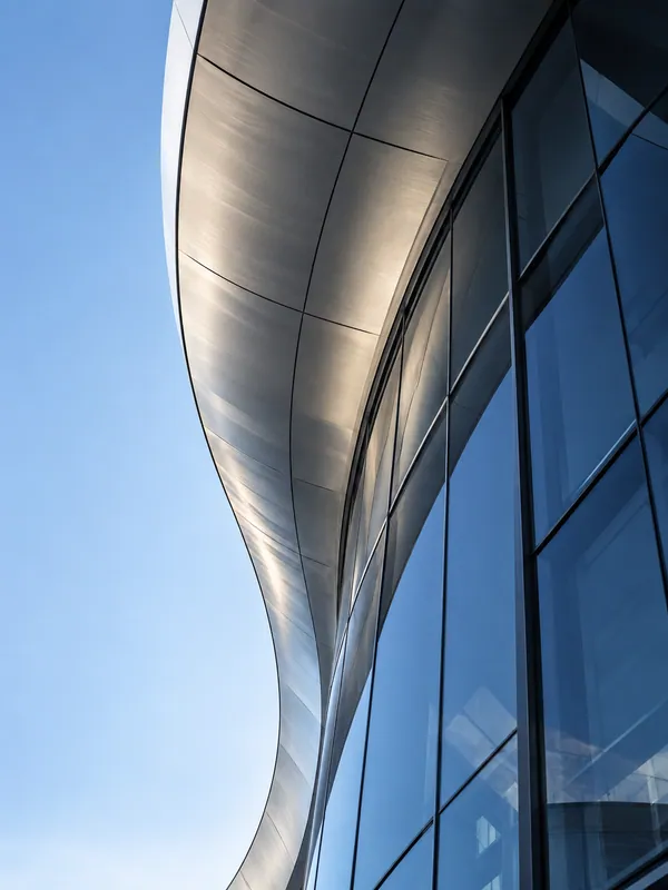 Curved silver canopy above a blue glass facade